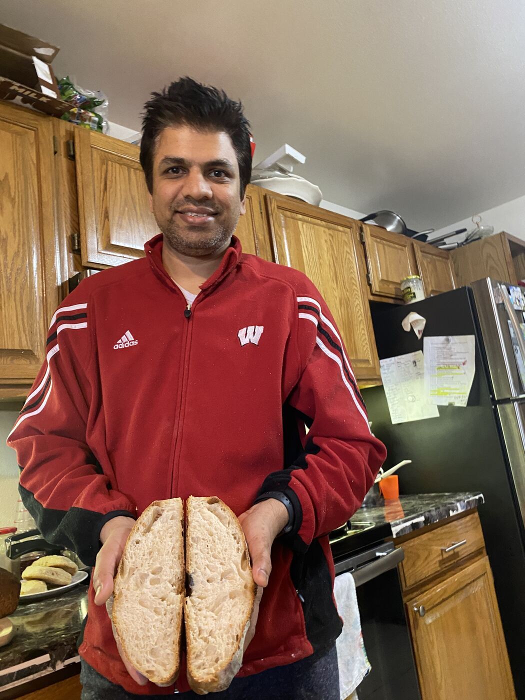 Naveen holding an early home-baked loaf in his kitchen in the United States