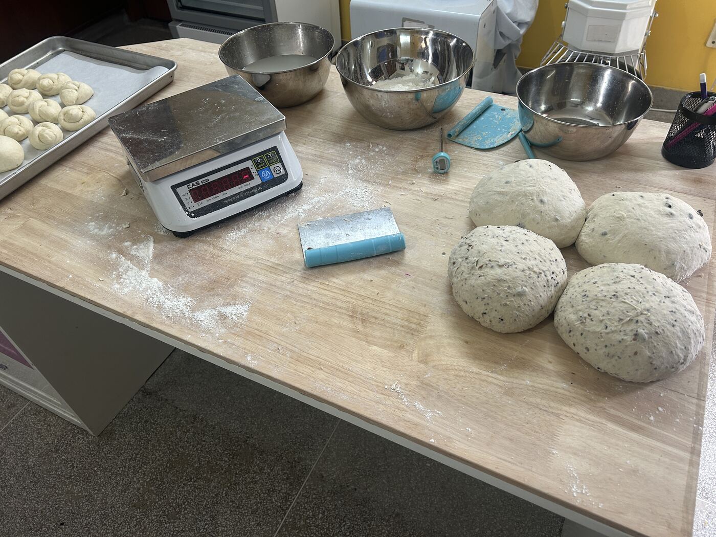 Buns and loaves being shaped in small batches on the bakery workbench